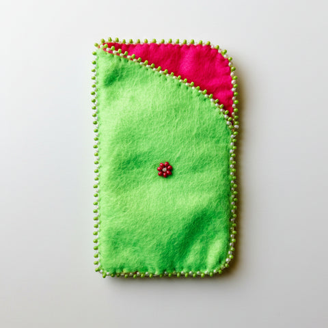 Green felt pouch with pink interior on a light wooden surface