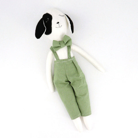 Stuffed dog toy with green overalls and bow tie on a white background