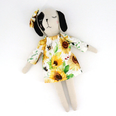 Stuffed toy dog wearing a sunflower dress on a white background