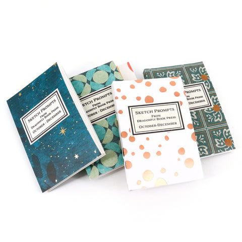 Four small notebooks with different designs on a white background