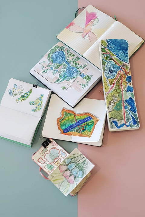 Collection of small notebooks with colorful illustrations on a concrete surface