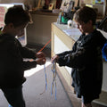Field trip image showing a Fur Trade Sash Weaving activity at the Little White Chapel, organized by Arts and Heritage Foundation St. Albert.